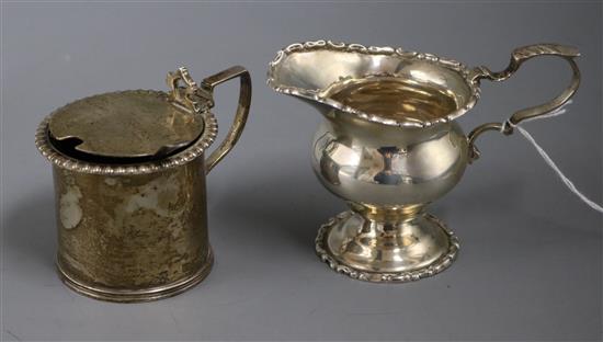 An Edwardian silver baluster cream jug, Chester 1909 and a silver drum shaped mustard pot.